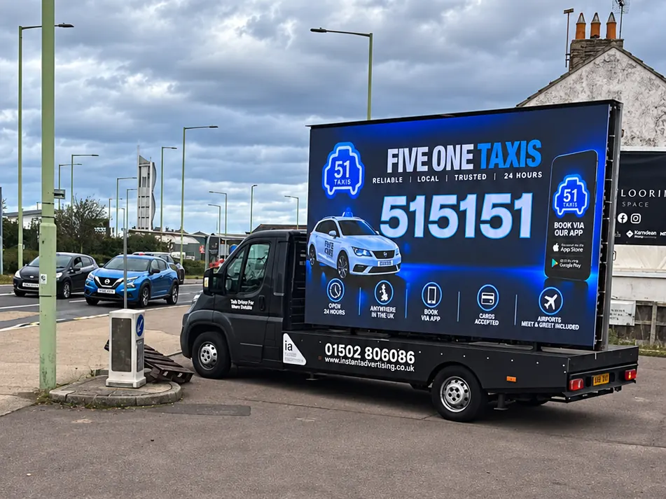 The digivan beside a main road showing an advert for 51 Taxis
