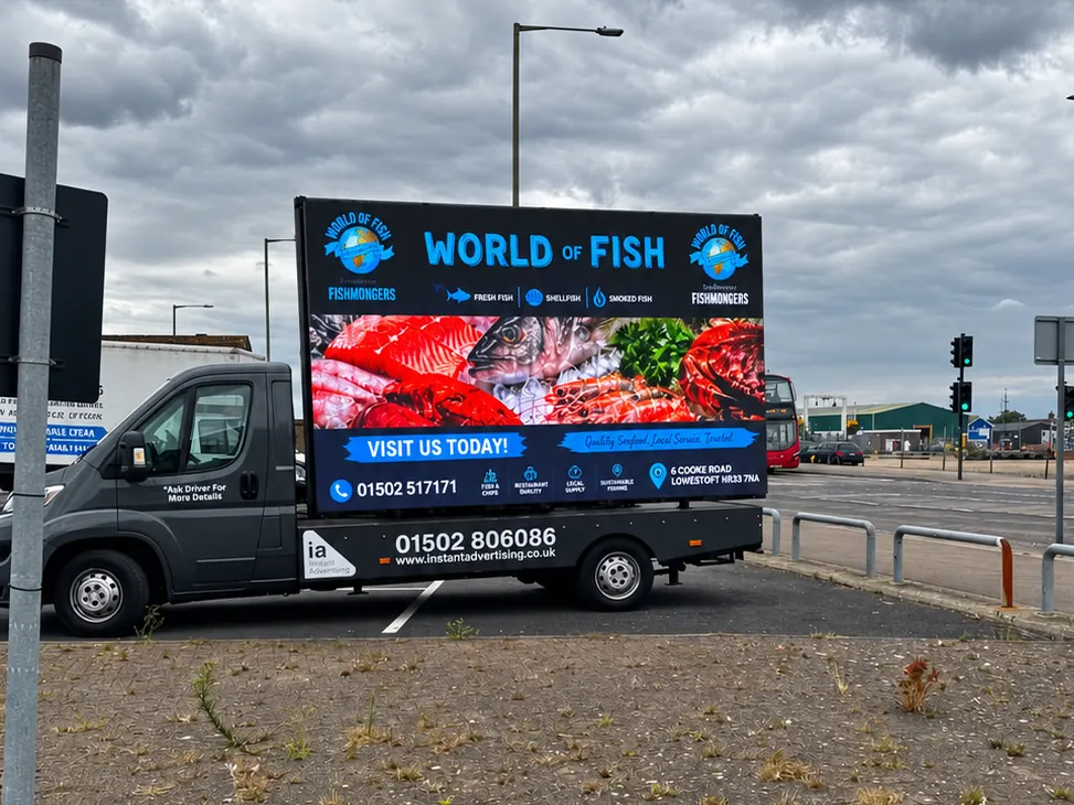 The Instant Advertising digivan, a dark grey flatbed van carrying a large LED screen, showing an advert for World of Fish